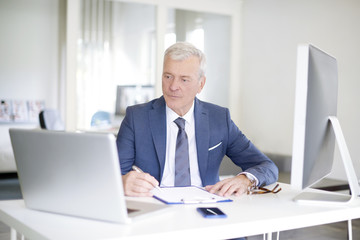 Senior professional businessman at work. Shot of a senior financial manager writing notes while...