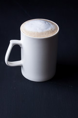A mug of latte coffee on a black background