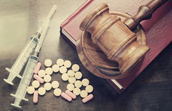 Narcotics concept, judge's gavel on legal book with drugs and syringes