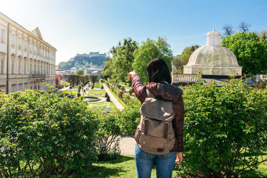 Austria. Salzburg. Woman tourist is standing at the entrance to the Mirabell Park and points his finger towards the fortress Hohensalzburg.