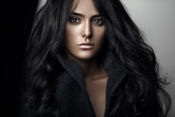 Fashion portrait of a sensual brunette girl with curly long black hair.