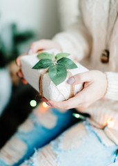 Christmas gift in the hands of women. Beautiful white packing with a sheet, toned light photo