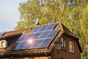 Hausdach mit Solarzellen, Satellitenschüssel und Alarmanlage