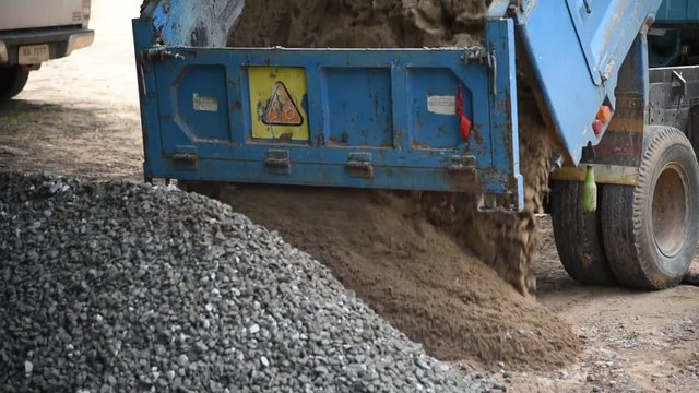 Dumper truck unloading soil or sand at construction site