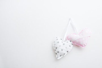 Two plush heart with dots, hanging on a white wall. The project on the card .