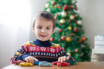 Adorable little preschool boy, playing with toy cars at home on