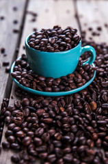 Turquoise cup with coffee beans on a wooden background. Beverage, tableware