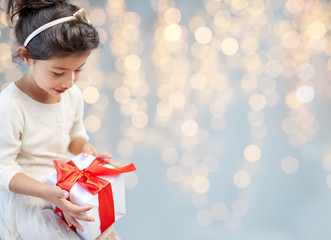 smiling little girl with gift box over lights