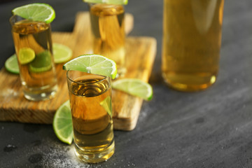 Gold tequila shots with lime and salt on gray table