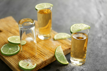Gold tequila shots with lime and salt on gray table