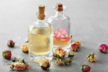 Bottles of aroma oil with roses on table