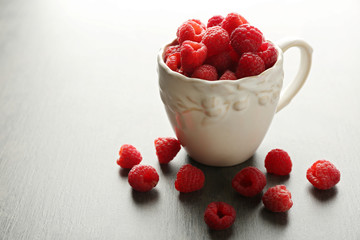 Fresh raspberries in cup on table