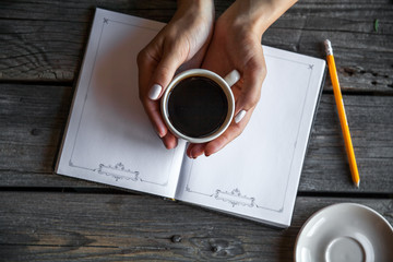 Female hand with a cup of coffee, taking notes. It works records. Business