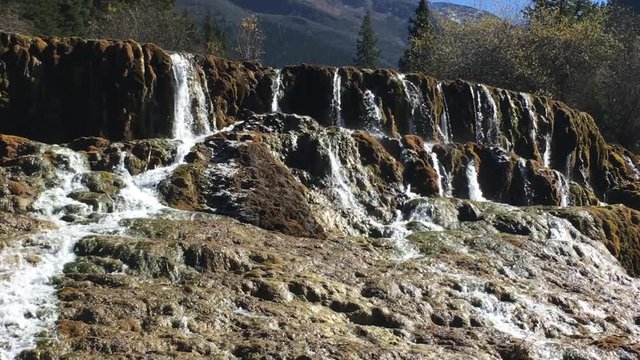 Waterfall stream at Huanglong Mountain with beautiful nature lime stone  in Sichuan , China on sunny day
