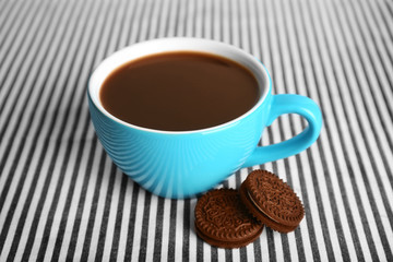 Cup of coffee and chocolate cookies with cream on fabric background