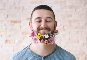 Handsome man with beard of flowers on light background