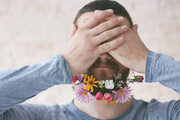 Man with beard of flowers on light background