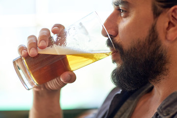 close up of man drinking beer at bar or pub