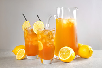 Fototapeta na wymiar Glasses and jug of iced tea with lemon slices on table
