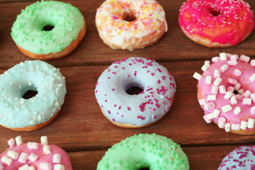 Tasty colorful donuts on wooden table, close up view