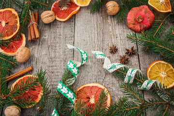 Christmas composition. Spruce branches, dried oranges, grapefruit, cinnamon, Christmas toys, walnuts, star anise, pomegranates on a wooden background.