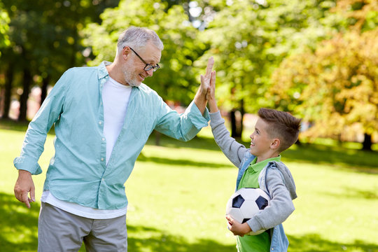 old man and boy with soccer ball making high five