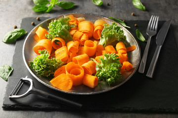 Plate with sliced carrot and lettuce on kitchen table