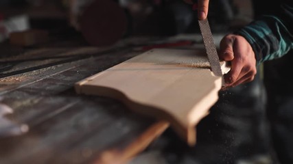 Close-up of a Carpenter working on a Wooden Window Frame with a File in his Workshop.
