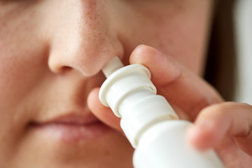 close up of sick woman using nasal spray