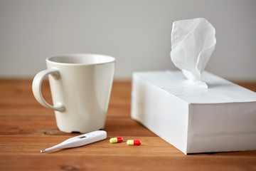 cup of tea, paper wipes and thermometer with pills