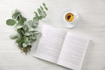 Green eucalyptus branches with cup of coffee on table