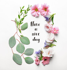Inscription "HAVE A NICE DAY" written on paper with flowers and leaves on white background