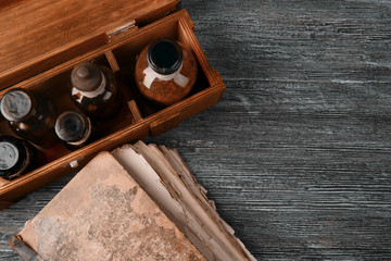 Vintage glass bottles in box with old book on wooden background, closeup