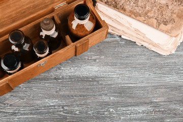 Vintage glass bottles in box with old book on wooden background, closeup