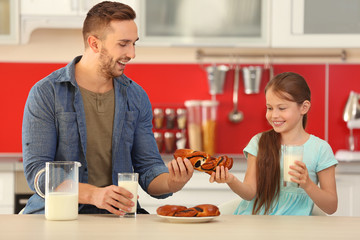 Father and daughter sharing bun at kitchen