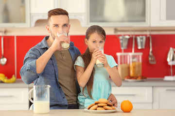 Father and daughter drinking fresh milk at kitchen