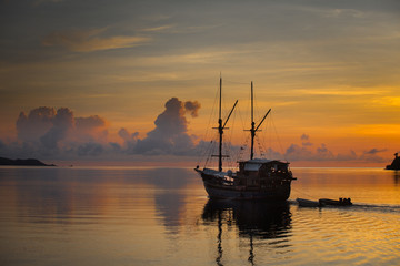 magical sunset over sea with a boat sailing in indonesia