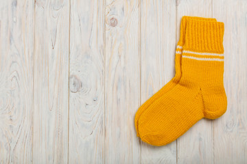 Knitted woolen socks yellow light on the wooden background.