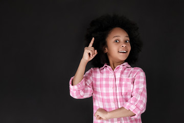 Good idea! Pretty girl pointing up while standing against blackboard. Copy space