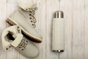 Winter light boots and a thermos in the knitted cover on the bri