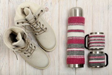 Winter light boots and a thermos in the knitted cover on the bri