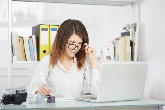 Young woman photo reporter sitting in front of desktop computer