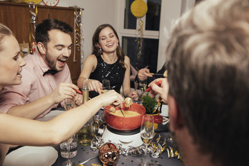 Friends eating cheese fondue on New Year's Eve