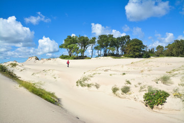 Fototapeta na wymiar Girl goes through the picturesque sand dunes