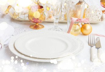 Tableware for christmas - set of empty plates and utencils on white tablecloth with defocused...