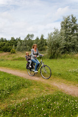 Fototapeta na wymiar Happy girl cycling behind grandmother on bike in nature