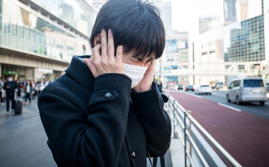 耳の穴をふさぐ男性
