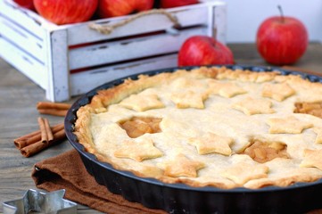 American apple pie with red apples and cinnamon on dark wooden background with white box