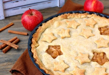 American apple pie with red apples and cinnamon on dark wooden background with white box