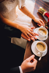 Fototapeta na wymiar luxury wedding couple holding hands and sitting in cafe in morning near window in soft light. elegant gorgeous bride and stylish groom in retro style. romantic moment